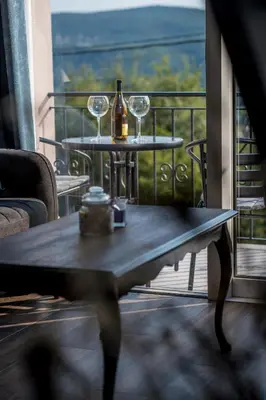 a table with wine glasses and a bottle on a balcony at Appartement en Chêne in Kotor