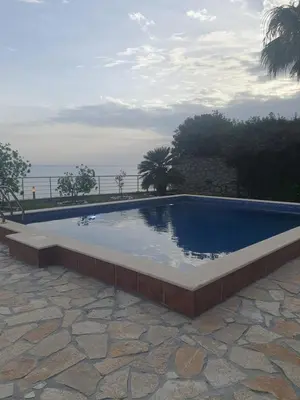 a large swimming pool in a patio with the ocean in the background at Aurora Spa in Kunje