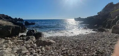 a rocky beach with the sun shining on the water at Aurora Spa in Kunje