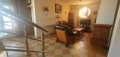 a living room with a staircase and a chair and a television at Aurora Spa in Kunje