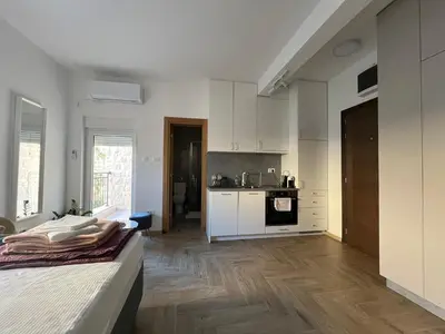 a kitchen with white cabinets and a bed in a room at DIS LUX Apartments in Radanovići