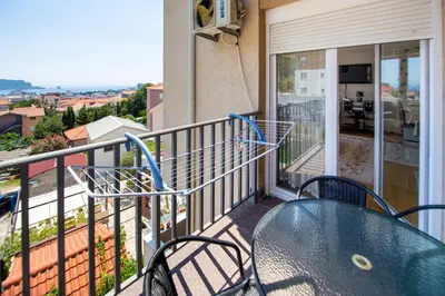 a balcony with a glass table and chairs at Sea view Lazi in Budva