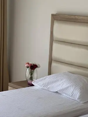 a bed with a vase of flowers on a table at Exclusive Apartments in Ulcinj