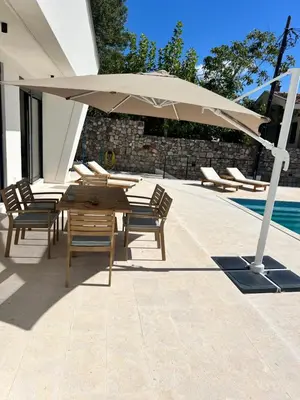 a table and chairs under an umbrella next to a pool at Villa Infinity Bar Montenegro in Brca