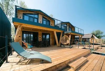 a house on a wooden deck with chairs on it at Villa Boga on Ada Bojana in Gornji Štoj