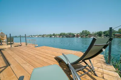 a chair sitting on a wooden dock next to the water at Villa Boga on Ada Bojana in Gornji Štoj