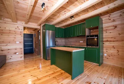a kitchen with green cabinets and a wooden floor at Villa Boga on Ada Bojana in Gornji Štoj