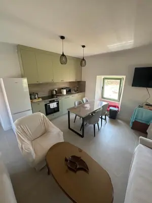 a living room with a table and a kitchen at Happy Holiday House Hava in Ravanj