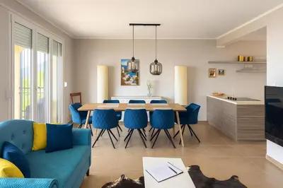 a living room with a dining room table and blue chairs at Million Star Villa in Lapčići