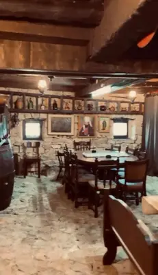 a dining room with tables and chairs and a stone wall at Etno Selo - Familie Raickovic in Podgorica