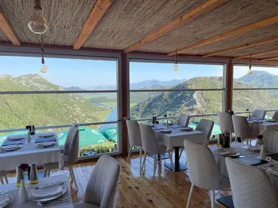 a restaurant with tables and chairs with mountains in the background at Konoba Ceklin in Cetinje