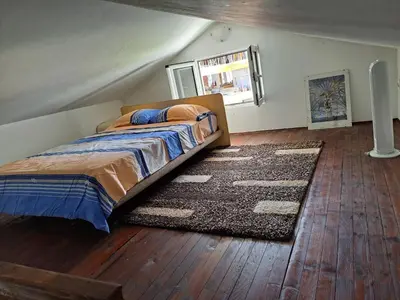 a bedroom with a bed and a rug on a wooden floor at Gallery apartment Budva in Budva