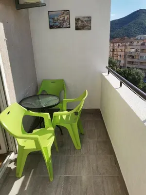 a balcony with two green chairs and a table at Gallery apartment Budva in Budva