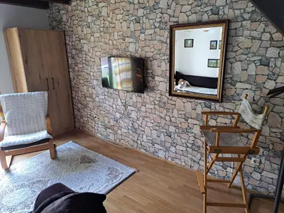 a room with a stone wall with a mirror and a chair at Gallery apartment Budva in Budva