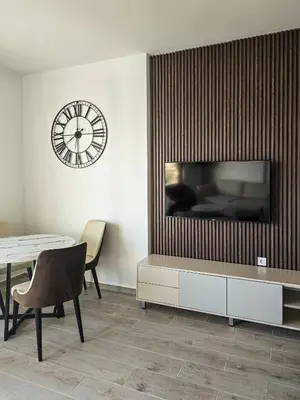 a living room with a table and a clock on the wall at Juzni Horizont Apartments in Sutomore