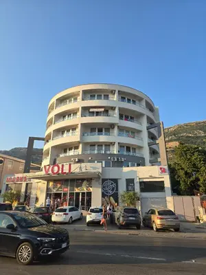 a tall building with cars parked in front of it at Juzni Horizont Apartments in Sutomore