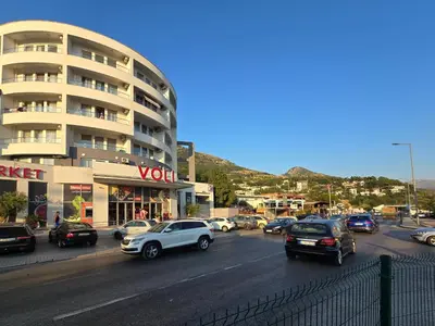 a busy city street with cars parked in front of a building at Juzni Horizont Apartments in Sutomore