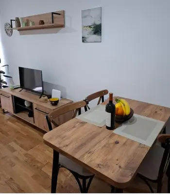 a wooden table with a bottle of wine and fruit on it at Apartman One in Budva
