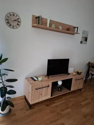 a television on a wooden cabinet in a room with a clock at Apartman One in Budva