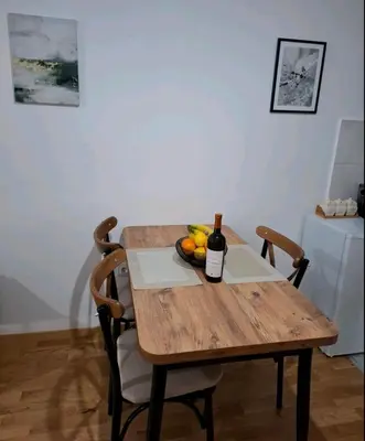 a wooden table with a bottle of wine and a bowl of fruit at Apartman One in Budva