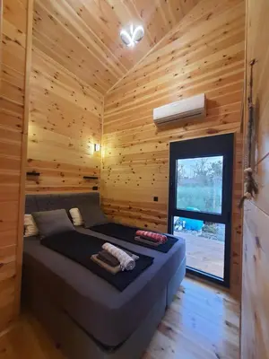 a bedroom with a bed in a wooden cabin at modernes Holzhaus, Cabin, auf dem Fluss, wenige Meter zum Meer in Ulcinj
