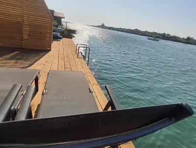 a dock with two benches and a boat in the water at modernes Holzhaus, Cabin, auf dem Fluss, wenige Meter zum Meer in Ulcinj