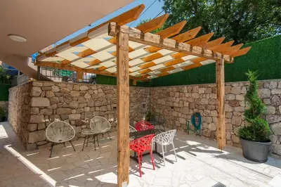 a wooden pergola with chairs and a table in a patio at Apartmani Vesna in Radanovići