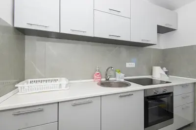 a kitchen with white cabinets and a sink at Apartmani Vesna in Radanovići