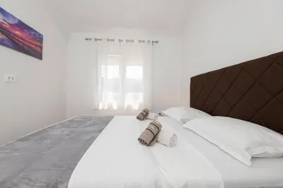 a bedroom with a large white bed with two pillows at Apartmani Vesna in Radanovići