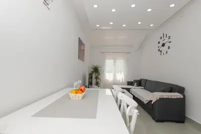 a white living room with a table and a couch at Apartmani Vesna in Radanovići