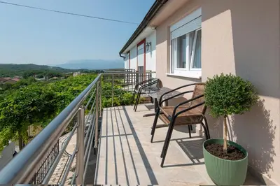 a balcony with chairs and plants on a building at Apartmani Vesna in Radanovići