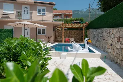 a swimming pool with two swans in a backyard at Apartmani Vesna in Radanovići