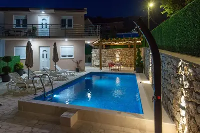 a swimming pool in front of a house at night at Apartmani Vesna in Radanovići