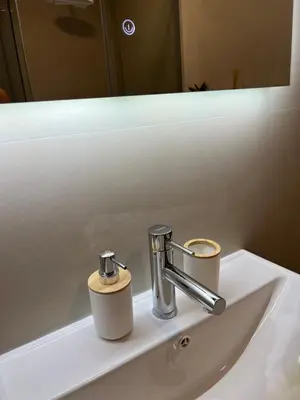 a bathroom sink with a faucet and two cups on it at Montenegro Luxury Suites - New City Podgorica in Podgorica