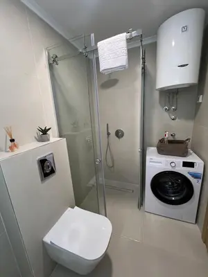 a bathroom with a shower and a toilet and a washing machine at Montenegro Luxury Suites - New City Podgorica in Podgorica
