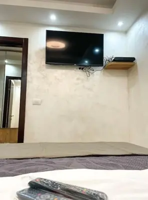 a bedroom with a tv on the wall with two remote controls at Tihanas apartment in Kotor