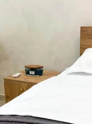 a bedroom with a bed and a wooden nightstand with a white bedspread at Tihanas apartment in Kotor