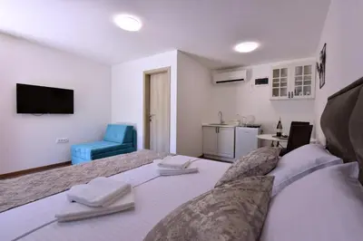 a bedroom with a large bed and a blue chair at Airport Apartments TRI HRASTA in Podgorica