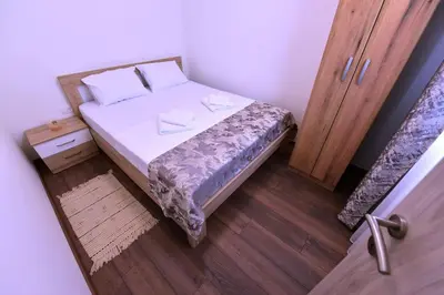 a small bedroom with a bed and a wooden floor at Airport Apartments TRI HRASTA in Podgorica