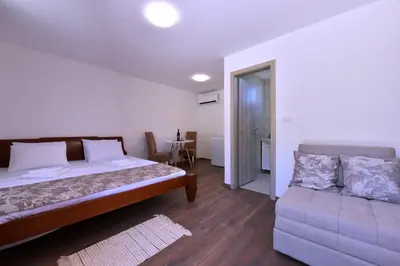 a bedroom with a bed and a couch at Airport Apartments TRI HRASTA in Podgorica