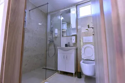 a bathroom with a toilet and a glass shower at Airport Apartments TRI HRASTA in Podgorica