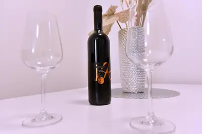 a bottle of wine next to two wine glasses at Airport Apartments TRI HRASTA in Podgorica