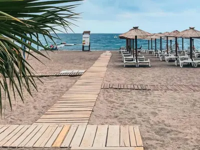 a sandy beach with chairs and umbrellas and the ocean at Studio Apartment Ljilja in Budva