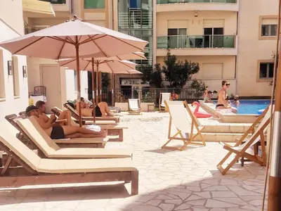 a group of people sitting in lounge chairs next to a pool at Studio Apartment Ljilja in Budva