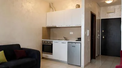 a kitchen with white cabinets and a couch in a room at Studio Apartment Ljilja in Budva