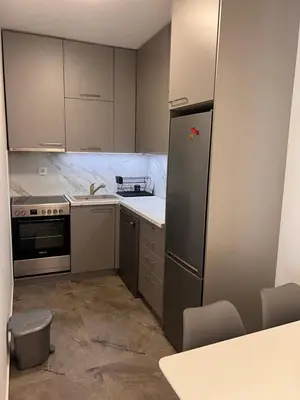 a kitchen with white cabinets and a refrigerator at Spring Apartment in Podgorica