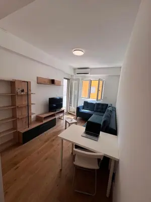 a living room with a bed and a table with a laptop at Spring Apartment in Podgorica