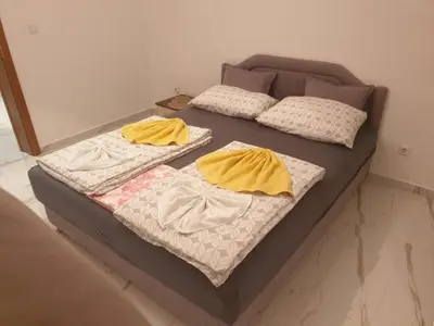 two beds with yellow sheets and pillows on them at Apartmani Gusani in Radanovići