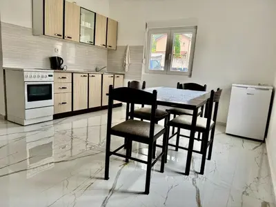 a kitchen with a table and chairs and a refrigerator at Apartmani Gusani in Radanovići