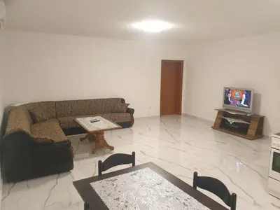 a living room with a couch and a table and a tv at Apartmani Gusani in Radanovići